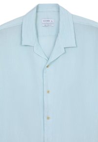 Camicia azzurra a maniche corte con vestibilità morbida. Realizzata in tessuto testurizzato, presenta un colletto e quattro chiusure a bottone con bottoni di colore chiaro.
