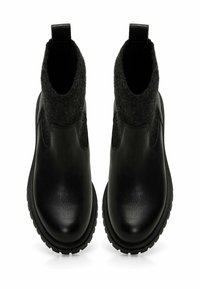 Botas negras hasta el tobillo de cuero con parte superior de lana texturizada, que cuentan con un acabado suave, suelas reforzadas y tiradores para fácil colocación.