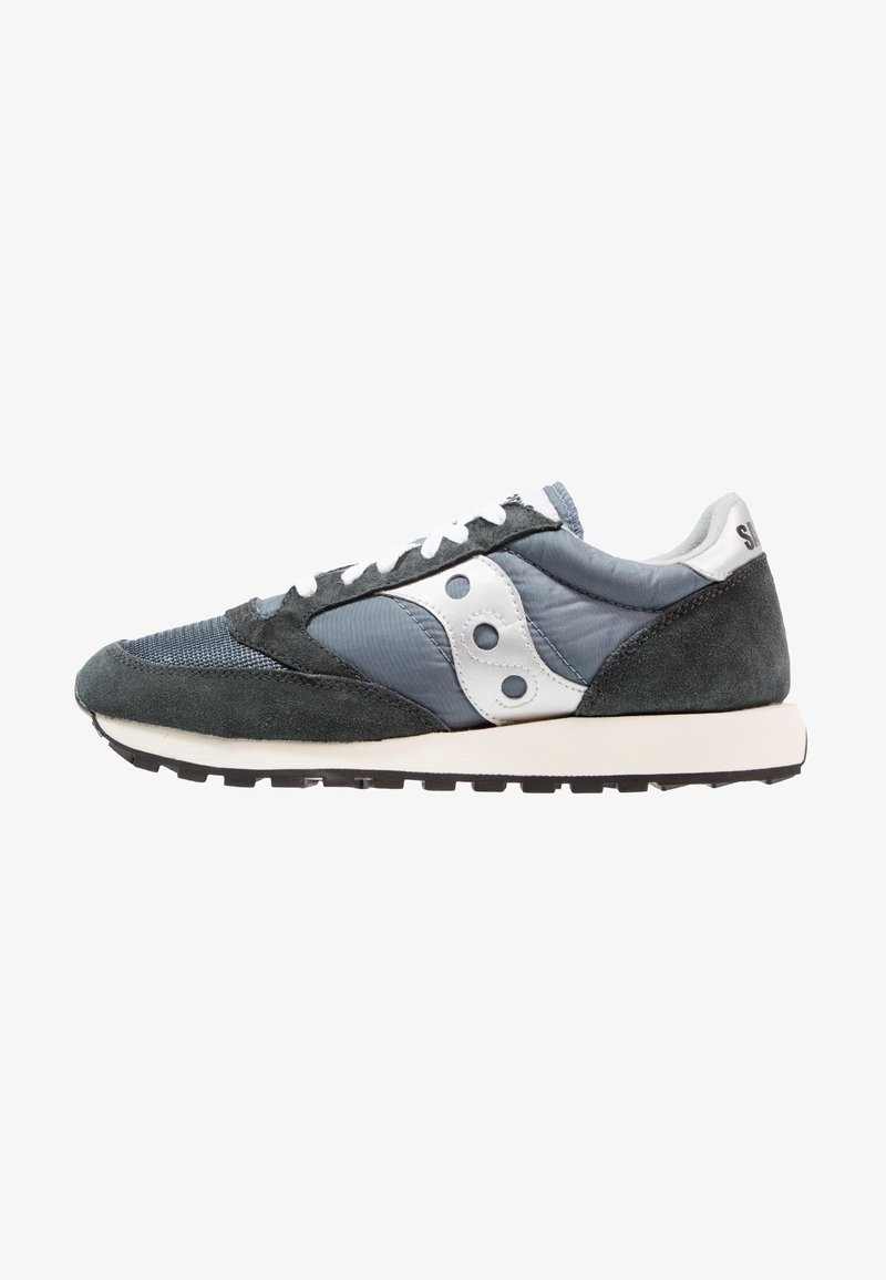 Sneakers med en overdel af grå mesh og ruskind, hvide læderdetaljer, sort gummisål og snørrebånd. Rund tå og retro design elementer.