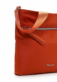 Orangefarbene Stoff-Schultertasche mit vorderer Reißverschlusstasche und passendem orangefarbenen Riemen, versehen mit kleinem Metall-"Tamaris"-Logo.