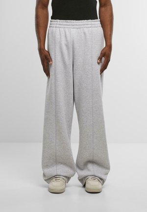 Jasnoszare dresy wykonane z miękkiego materiału, z elastycznym pasem, charakteryzujące się luźnym krojem i detalami wzdłuż szwów. W połączeniu z jasnymi sneakersami.