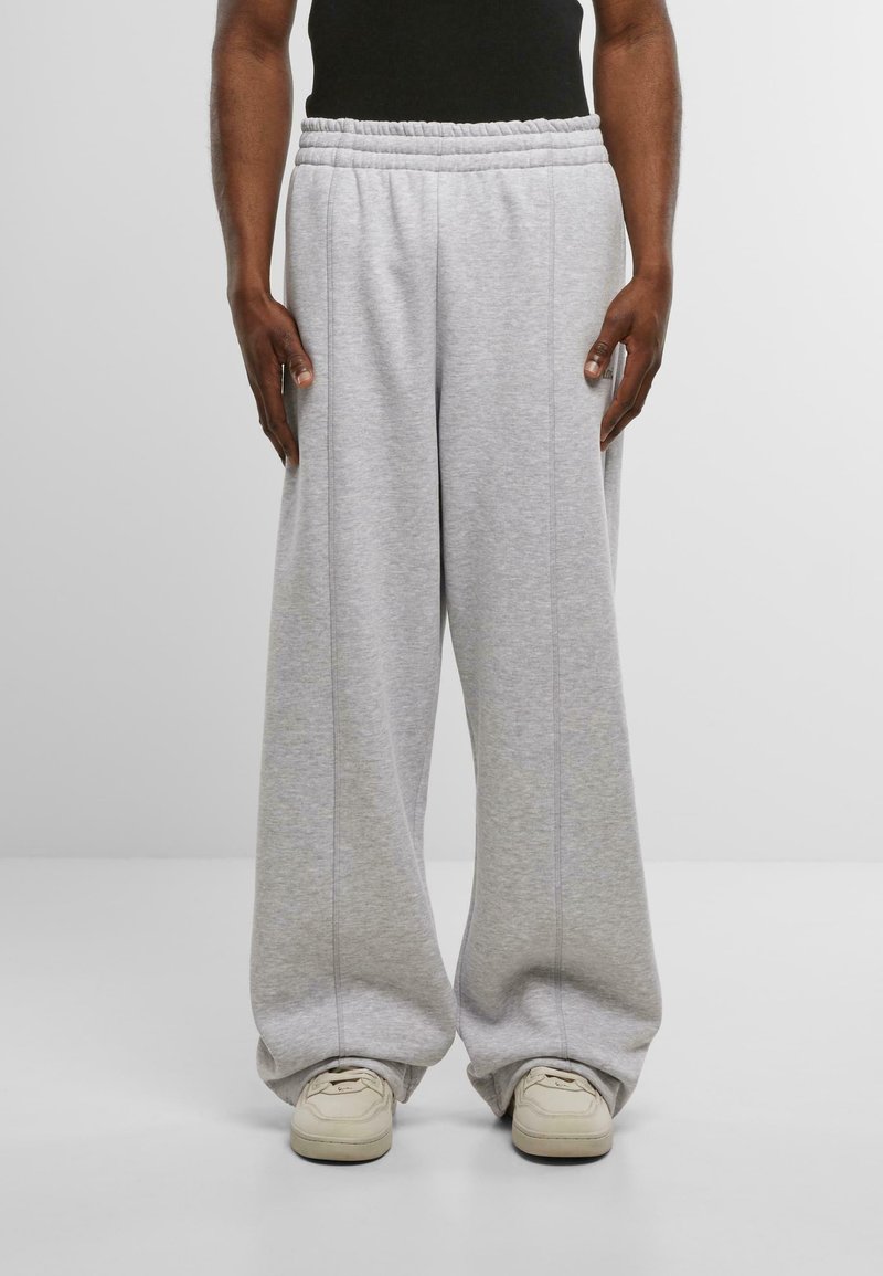 Gaiši pelēkas sporta bikses, kas izgatavotas no mīksta auduma ar elastīgu jostasvietu, piedāvā brīvu piegriezumu un sānu šuvju detaļas. Pāris ar gaišiem sporta apaviem.