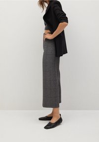 Pantalons gris à carreaux avec un design droit et court. Associés à un blazer noir et des chaussures plates noires ; texture de tissu lisse.