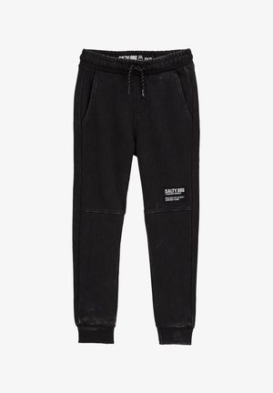 Musta verkkarit, joissa on joustava vyötärönauha, kiristysnyöri, sivutaskut, resorit lahkeensuissa ja "SALTY DOG" -logopatch vasemmassa reidessä.