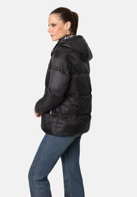 Chaqueta de plumas negra con capucha, que presenta secciones acolchadas horizontales y un acabado ligero y brillante. Incluye un forro interior con un patrón.