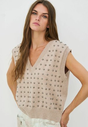 Beige gebreid vest met een V-hals, korte mouwen en metalen studs gelijkmatig verdeeld over de voorkant.