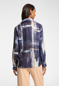 Camicia a maniche lunghe con un motivo astratto multicolore in blu navy, crema e verde teal. Tessuto leggero con colletto e polsini con bottoni.