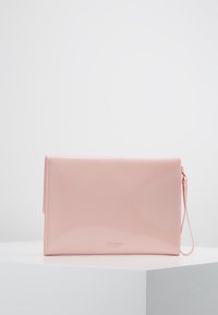 Pochette en cuir verni rose avec une texture lisse, fermeture éclair et bracelet pour poignet ; logo de la marque imprimé en police discrète.