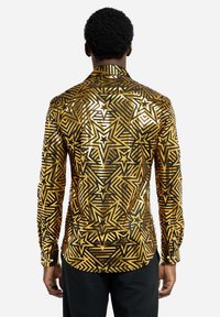 Langærmet skjorte med et sort og guld stjernemønster, geometriske designs og en glat finish. Knaplåse ved håndleddene og en klassisk krave.