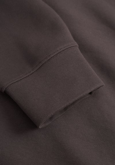 Dark brown sweatshirt fabric with a ribbed cuff and smooth texture. Features a clean finish without visible seams on the cuff.