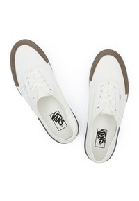 White canvas sneakers with brown rubber toe caps and black soles. Features classic lace-up design and Vans logo on the tongue.