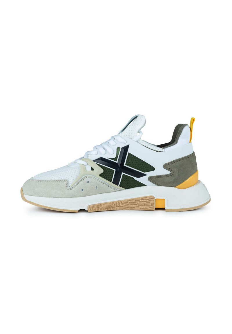 Zapatilla deportiva blanca con detalles en gris y oliva, que presenta una parte superior de malla, elementos de ante texturizado y una suela de goma con un patrón en forma de panal.