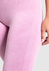 Leggings rosa chiaro realizzati in un tessuto testurizzato con sottili motivi a righe, progettati con una silhouette aderente e una finitura liscia.