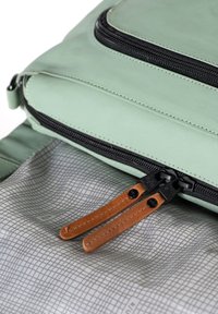 Borsa verde chiaro con una cerniera nera, dotata di pomelli in pelle marrone. L'interno presenta un motivo geometrico grigio. Texture complessiva liscia.