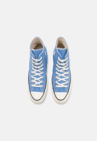 Höga sneakers i ljusblå canvas med vit gummitå och snören. Har en logotyp-patch på utsidan.