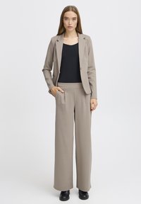 Bežna krojena blazer in široke hlače, narejene iz mehkega materiala. Obleka ima stranske žepe in klasičen kroj s čistimi linijami.