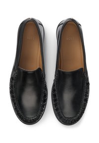 Μαύρα δερμάτινα παπούτσια slip-on με λεία υφή, στρογγυλεμένη μύτη και διακοσμητική ραφή κατά μήκος των άκρων. Διαθέτουν λογότυπο στην εσωτερική σόλα.