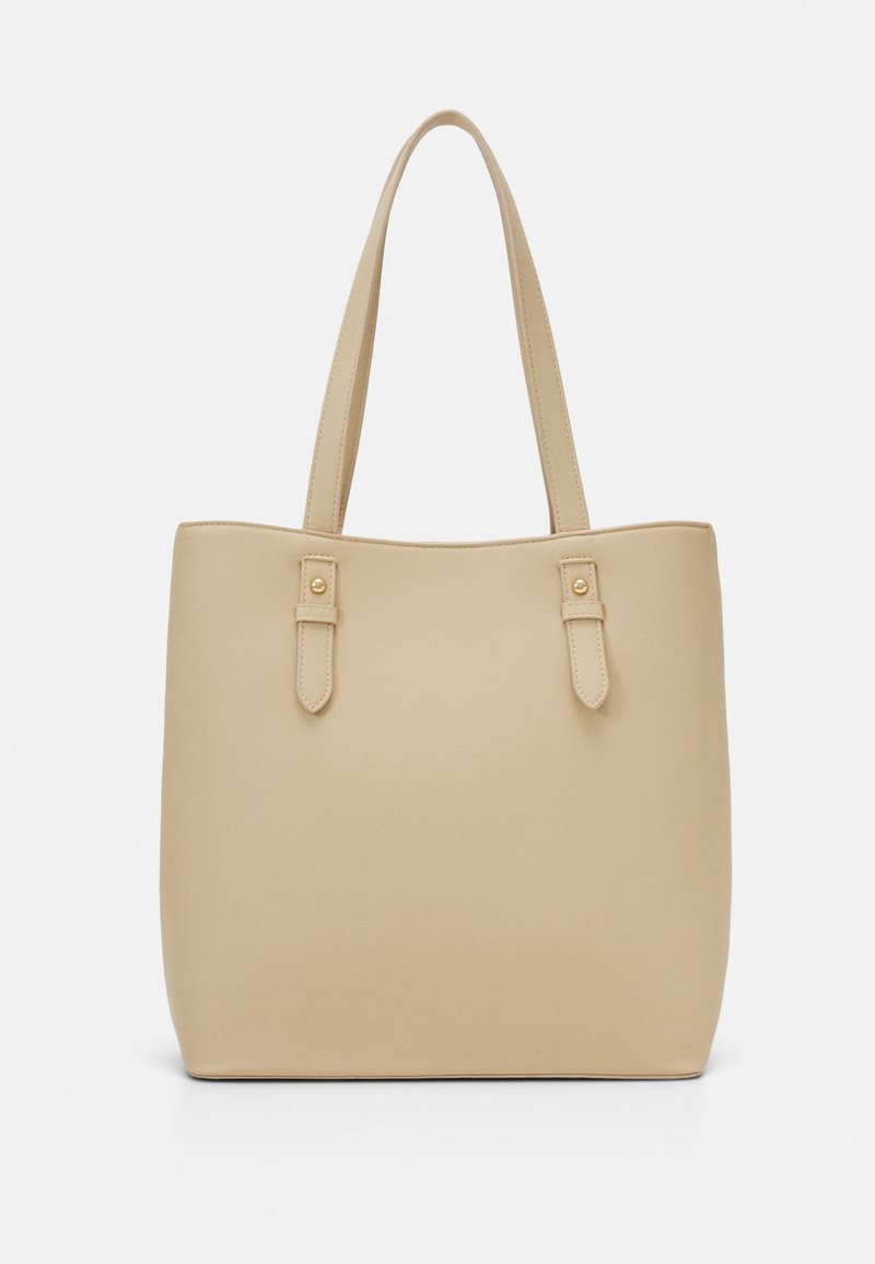 Sac fourre-tout en cuir beige avec deux poignées parallèles et détails de lanières décoratives avec boutons dorés sur fond blanc.