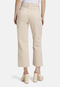 Beżowe, krótkie, szerokie spodnie z surowym wykończeniem. Posiadają dwie tylne kieszenie i dopasowany pas. Gładki, bawełniany materiał o subtelnej teksturze.