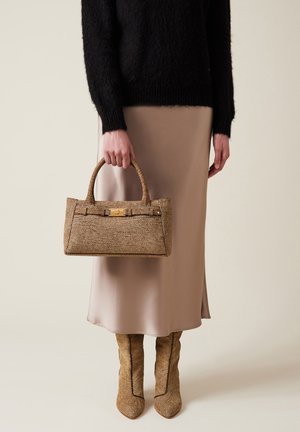 Taschen im Tan-Textur mit strukturierter Form, goldenen Hardware-Details und zwei kurzen Griffen, kombiniert mit einem seidigen beigefarbenen Rock und gemusterten Stiefeln.
