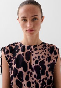 Mouwloze blouse met luipaardprint van zachte stof, met een sleutelgat halslijn, donkerpaarse en roze patronen, en gestrikte details op de schouders.