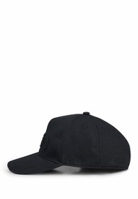 Svart baseballkeps i bomull med en strukturerad, rundad skärm. Har en tonad broderad logotyp fram och lufthål för ventilation.