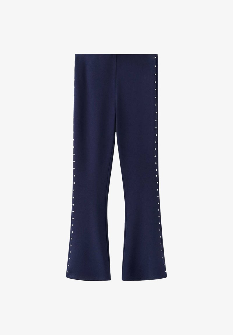 Pantalon évasé bleu marine avec de petits clous argentés courant verticalement le long des coutures extérieures des deux jambes.