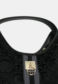 Borsa a mano in velluto nero con motivo floreale in rilievo, tracolla ampia, hardware in tono oro e placca centrale con logo. Interno testurizzato visibile.