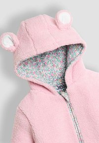 Giacca con cappuccio in pile rosa con orecchie di orso, caratterizzata da una fodera con stampa floreale. Chiusura con zip e materiale morbido e texture.