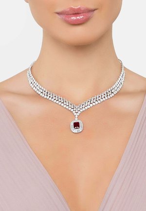 Silver multi-strand necklace featuring clear rhinestones and a central red gem surrounded by a decorative silver setting. Shiny finish.