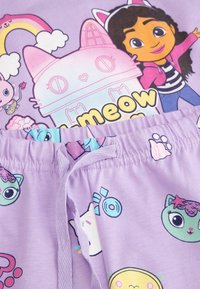 Fioletowe bawełniane spodenki z regulowanym sznurkiem w talii oraz zabawnymi nadrukami postaci, chmur i wzorów na gładkim materiale.