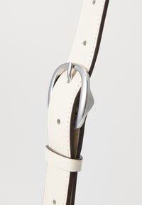 White leather belt with brown accents, featuring a silver metal buckle and several adjustment holes along its length. Smooth texture.