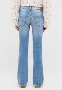 Jasnoniebieskie dżinsy w fasonie dzwonów, wykonane z denimu. Posiadają klasyczny pięciokomorowy styl oraz kontrastowe przeszycia na tylnych kieszeniach.