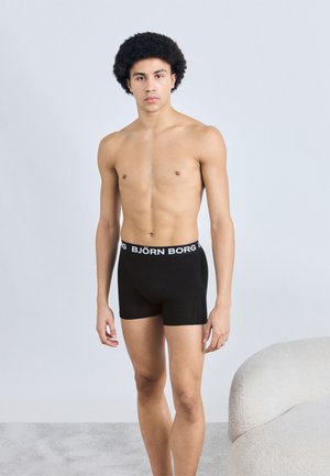 Boxers noirs avec un logo blanc "BJÖRN BORG" sur la ceinture élastique. Le tissu semble lisse et ajusté, avec une longueur de jambe courte standard.