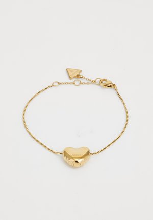 Goldenes Armband mit einem herzförmigen Charm, das eine strukturierte Oberfläche und den eingravierten Markennamen aufweist. Kabelkette mit einem Karabinerverschluss und einem dreieckigen Tag.