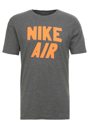 Grijs T-shirt met korte mouwen en ronde hals, met grote oranje "NIKE AIR" tekst op de voorkant gedrukt.