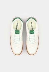 Weiße Ledersneaker mit grünen Akzenten, ausgestattet mit einer strukturierten Gummi-Sohle, runder Zehenpartie und klassischem Schnürdesign.