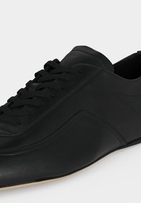 Μαύρο δερμάτινο αντρικό επίσημο παπούτσι με κορδόνια, λείο φινίρισμα και διακριτική ραφή σε ανοιχτό φόντο.