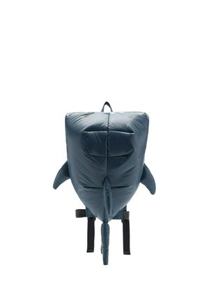 Rucsac moale, căptușit, în formă de rechin albastru, cu aripioare, coadă și bretele negre reglabile pe un fundal alb.