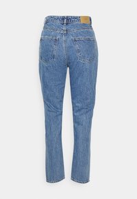 Jeans de denim azul claro com corte reto, cinco bolsos e um rótulo de couro na parte de trás da cintura, com uma textura desbotada.