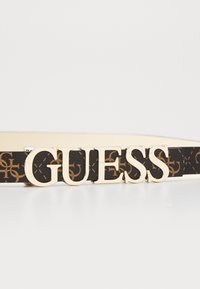 Juodas diržas iš dirbtinės odos su auksiniais aksesuarais, ant kurių yra „GUESS“ logotipas, turintis pakartotinį logotipo raštą rudos spalvos. Lygus paviršius, elegantiškas dizainas.