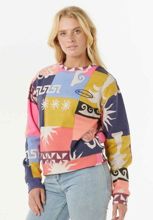 Sudadera colorida con varios patrones abstractos en rosa, púrpura, amarillo y azul; está hecha de una tela suave con un cuello de canalé.
