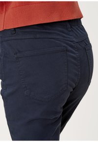 Niebieskie spodnie z bawełny z domieszką, o gładkiej teksturze, z dwoma tylnymi kieszeniami i widocznymi detalami szwów. Elastyczny pas dla wygody.