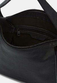 Czarna skórzana torebka o teksturowanej powierzchni, z zamykaną na zamek komorą i subtelnym podszyciem. Gładki pasek dołączony.