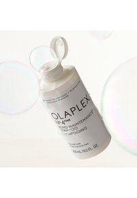 Olaplex No. 4 Fine Bond Maintenance Shampoo-flaska. Vit plast, cylindrisk form, pump-lock, svart text och vattenbubblor runtom.