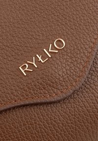 Brązowy portfel z teksturowanej skóry z logo "RYŁKO" w złotym kolorze na przedniej stronie, z przeszytym brzegiem w jaśniejszym odcieniu.