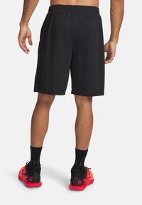 Μαύρα αθλητικά σορτς με ελαστική μέση, λεία υφή, μήκος μέχρι το γόνατο, συνδυασμένα με κόκκινα και μαύρα αθλητικά παπούτσια και μαύρες κάλτσες αστραγάλου.