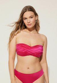 Conjunto de bikini en un vibrante color rosa, que presenta un top sin tirantes con un diseño de pliegues y una parte inferior de tiro bajo a juego, fabricado con suave tejido elástico.