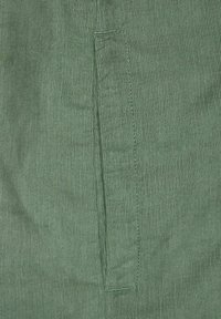 Groene corduroy stof met verticale strepen, voorzien van een subtiele textuur en een gestikte pocketdetail aan de zijkant.