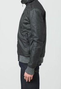 Sort læderjakke med høj krave, lynlåslommer og grå strikkede manchetter. Slank, tætsiddende design med en glat, tekstureret finish.